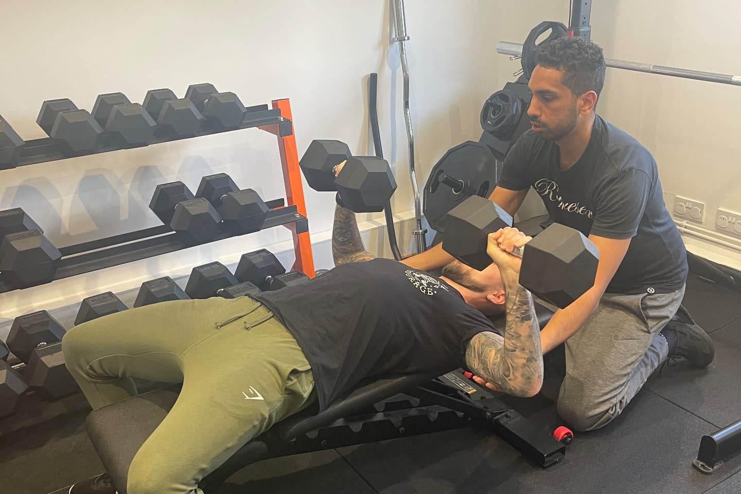 Sam spotting a client during a dumbbell bench press in the private studio